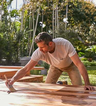 person staining a deck outside