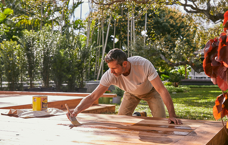 person staining a deck outside